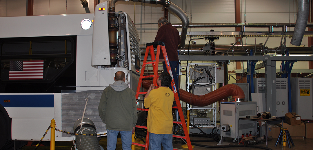 men attaching emissions equipment to a bus